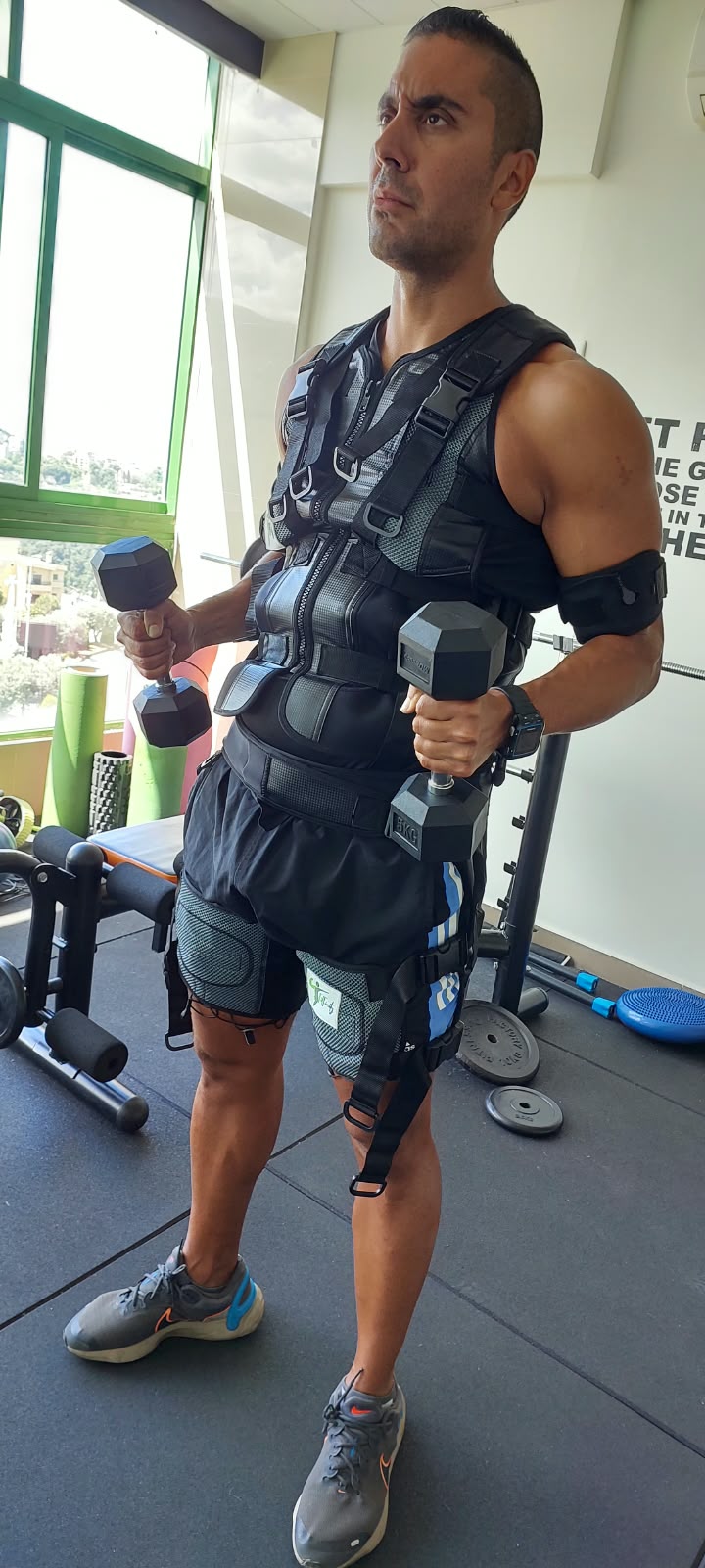 A client using dumbbells while wearing EMS equipment